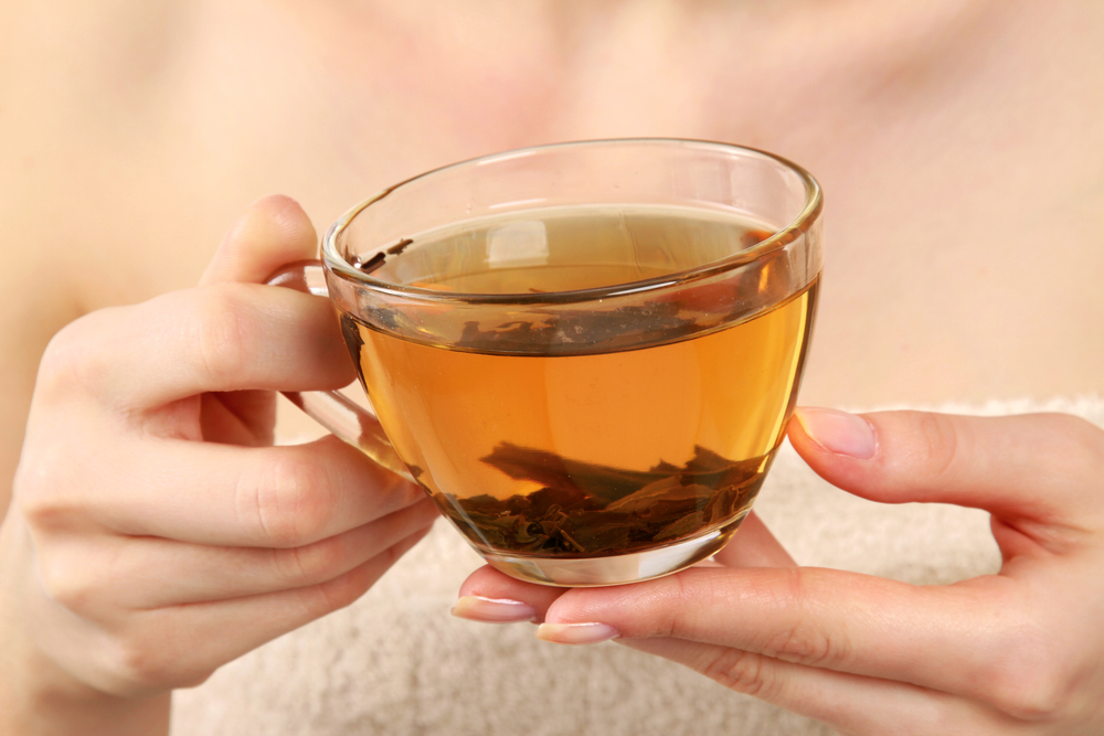 Woman holding a cup of green tea in her hands. 